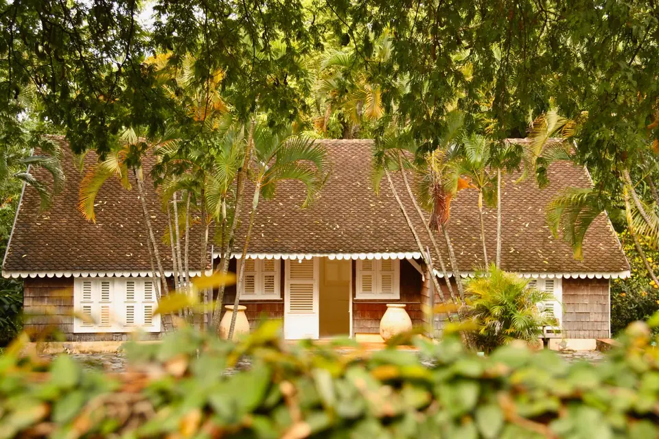 Maison basse à véranda noyée dans la végétation tropicale