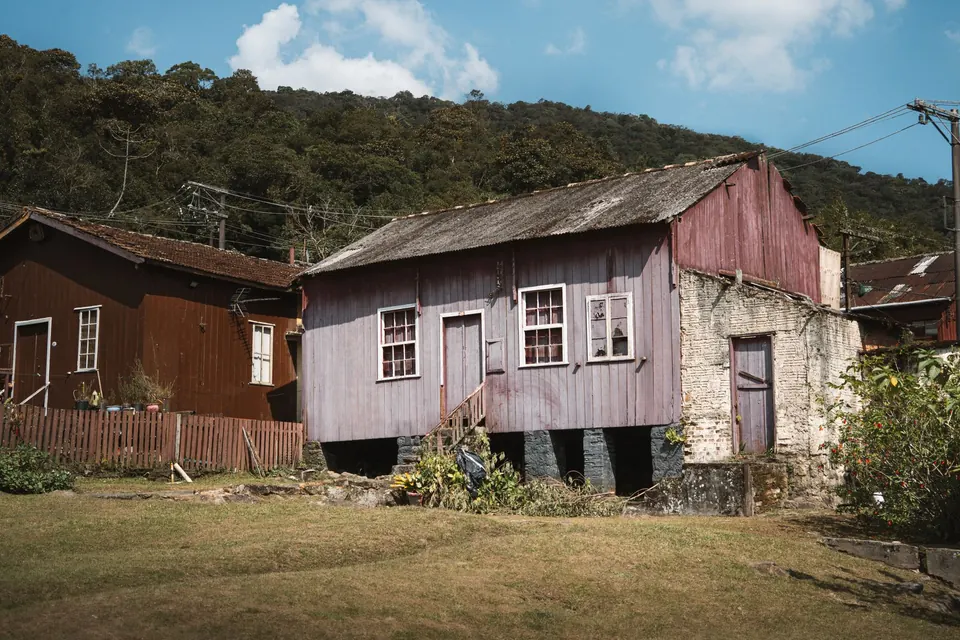 Maisons en bois à toiture de tôle, au pied d'une colline boisée