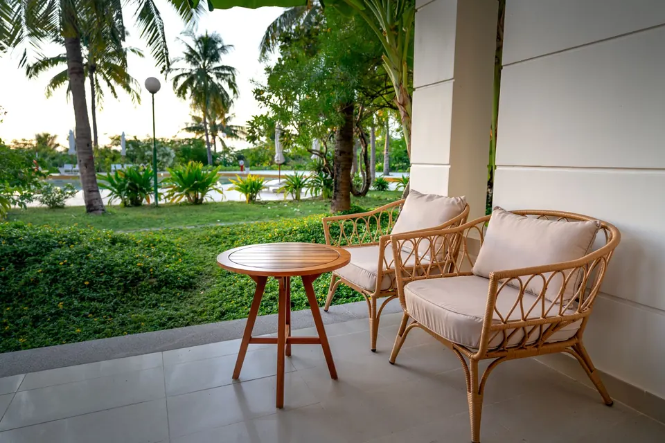 Varangue avec fauteuils en rotin ouverte sur un jardin de palmiers